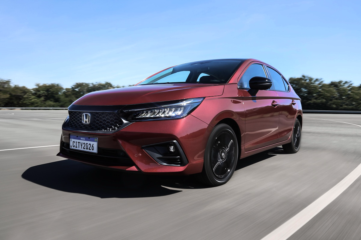 Honda City hatch vermelho e preto em uma pista, visto de frente e pela lateral.