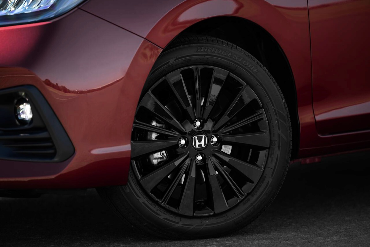 Roda preta de liga leve com logotipo Honda em um carro vermelho.