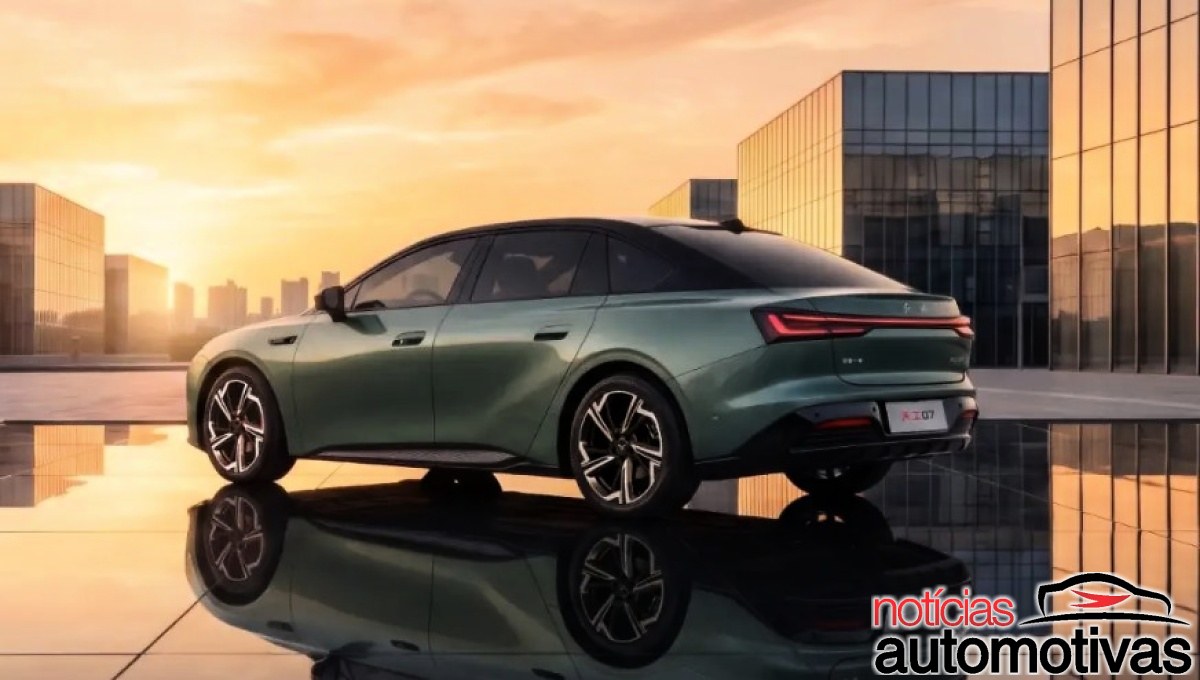 Sedã Hongqi Tiangong 07 verde visto de trás, diante de edifícios envidraçados ao entardecer.