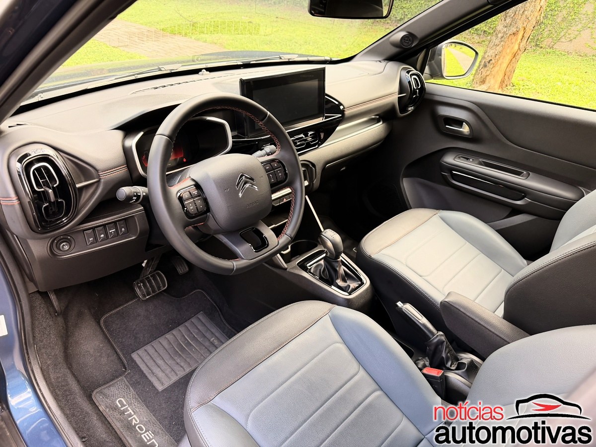 Interior dianteiro do Citroën Aircross com volante, painel digital, tela central e bancos claros.