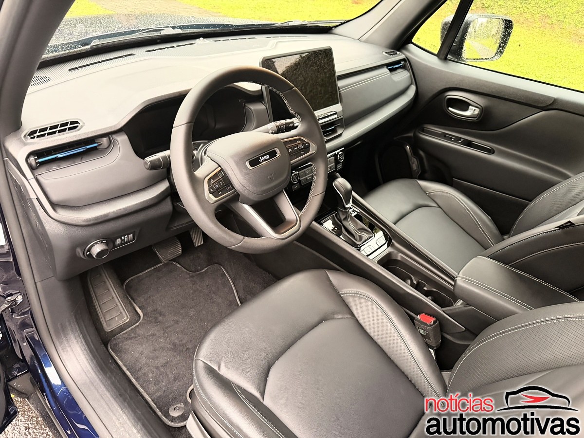 Interior dianteiro do Jeep Renegade com volante, central multimídia, console e bancos pretos.