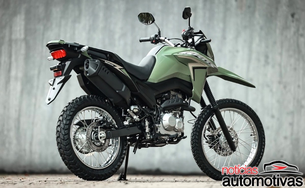 Honda NXR160 Bros verde vista de lado e por trás, parada diante de uma parede cinza.