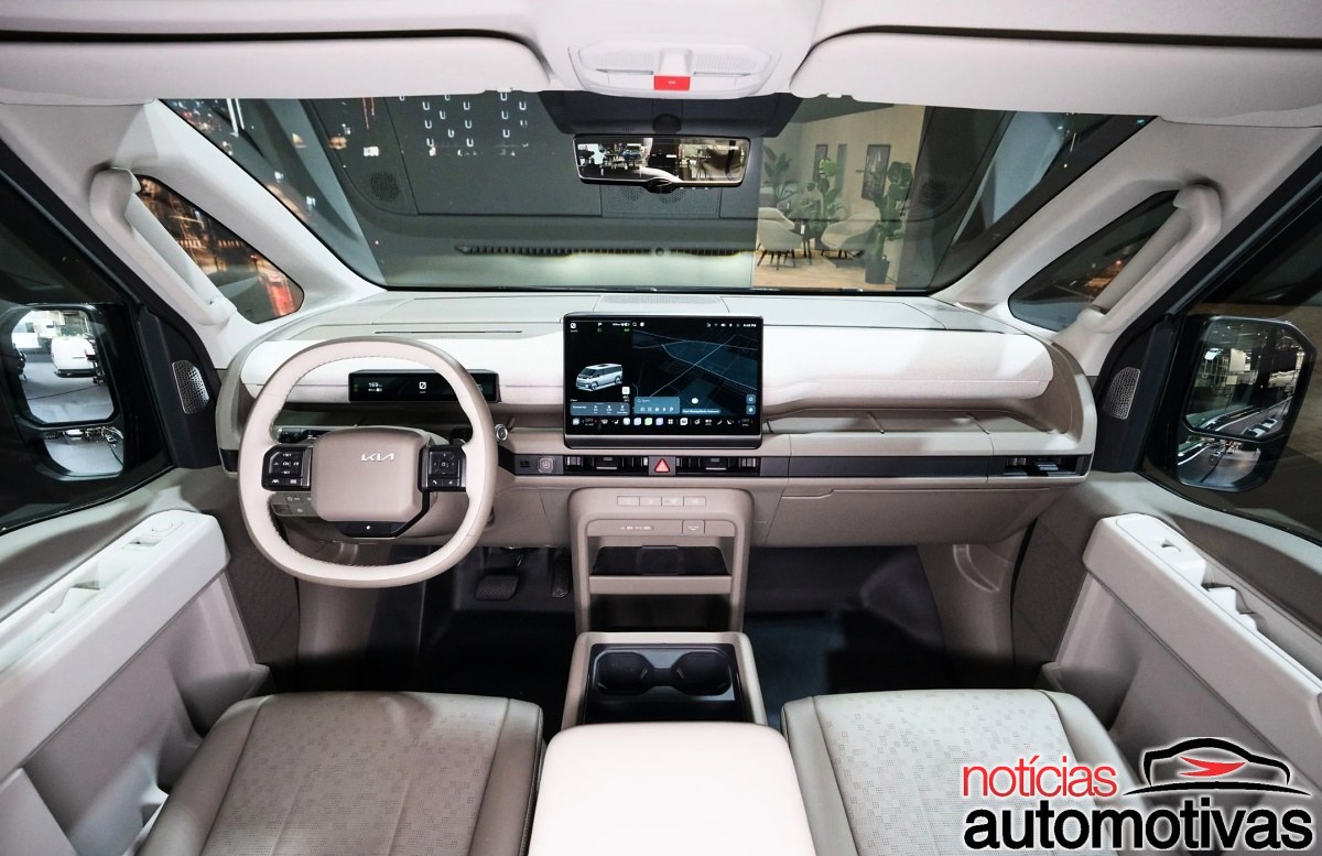 Interior dianteiro da Kia PV7, com volante de dois raios, painel digital e tela central sobre o console.