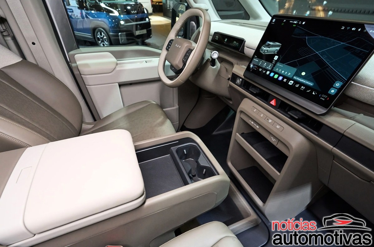 Console dianteiro da Kia PV7 com volante, tela central, porta-objetos e dois porta-copos.