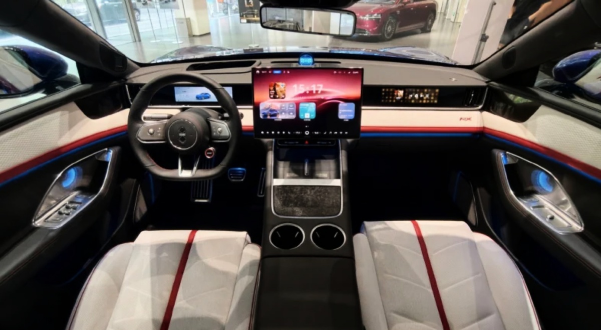 Interior do Luxeed RX com volante, painel digital, tela central, console e bancos dianteiros brancos.