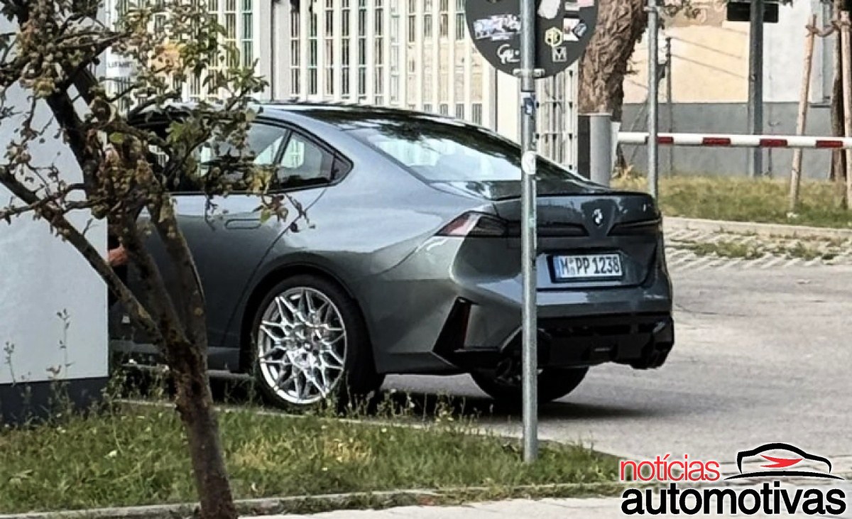 Sedã BMW cinza-escuro visto de trás e de lado, com rodas prateadas, quatro saídas de escape e placa M PP 1238.