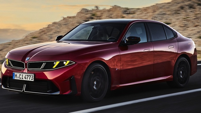 Sedã vermelho da BMW em movimento, visto de frente e de lado, em uma estrada entre rochas.