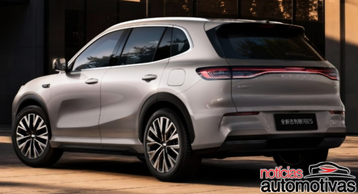 SUV Geely Galaxy E5 em tom cinza-claro, visto pela traseira e pela lateral, diante de um edifício.