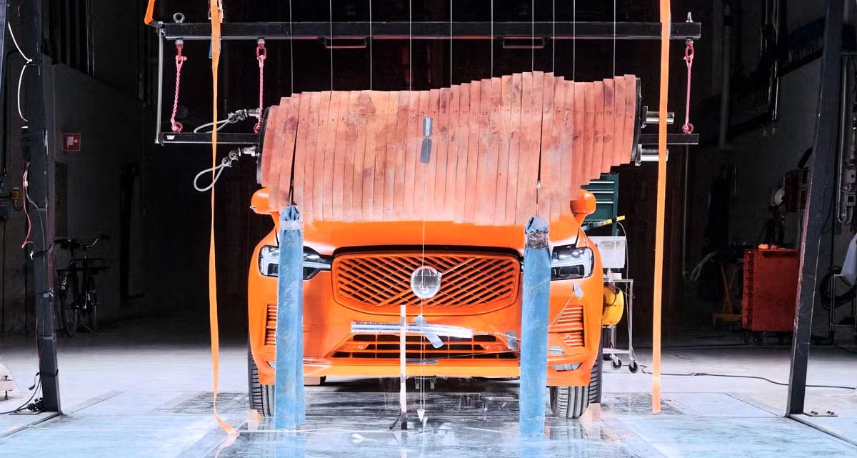 SUV Volvo laranja visto de frente, sob um boneco de alce suspenso em um laboratório.