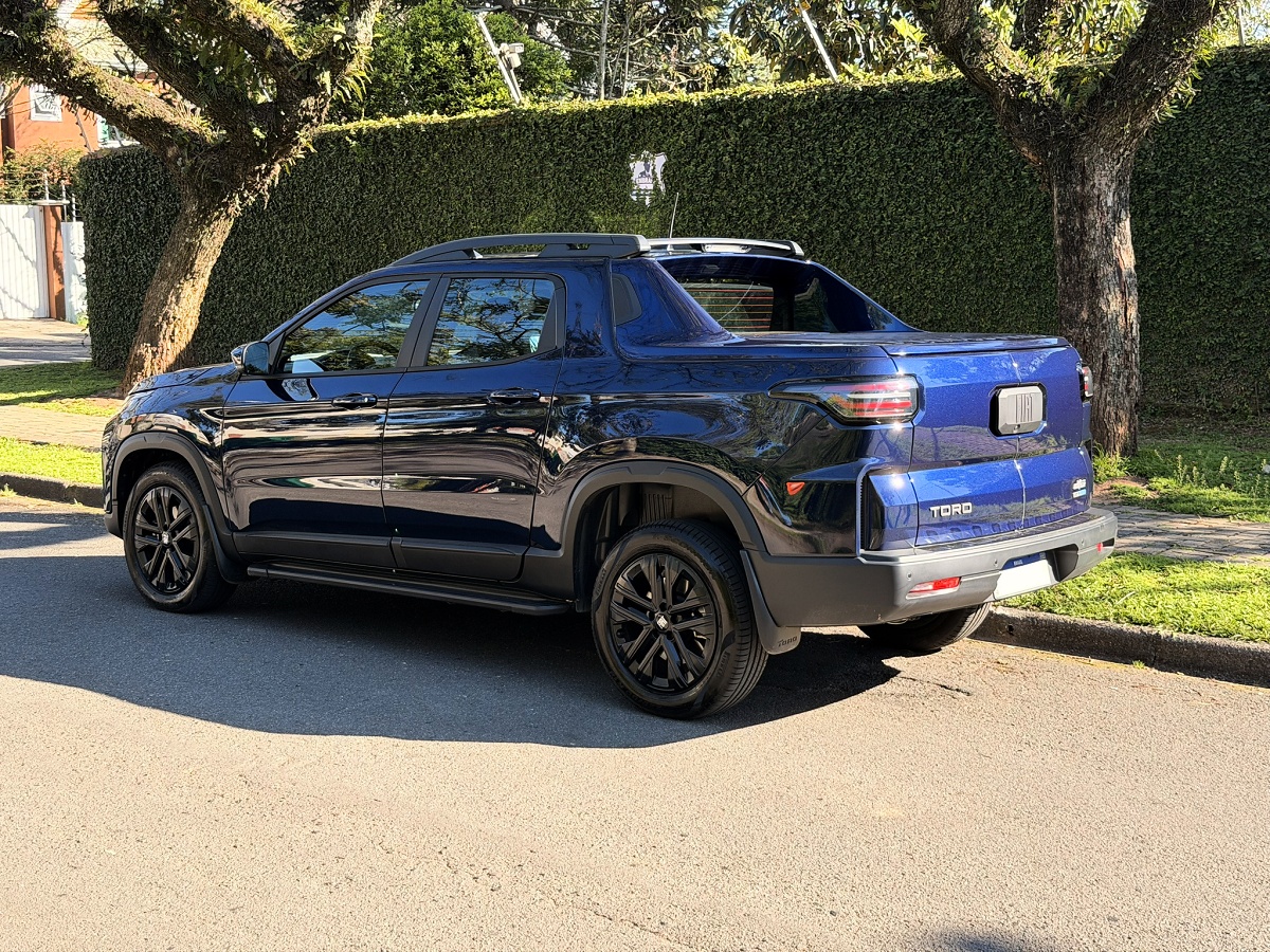 Fiat Toro azul-escura vista por trás e de lado, com a tampa da caçamba fechada.