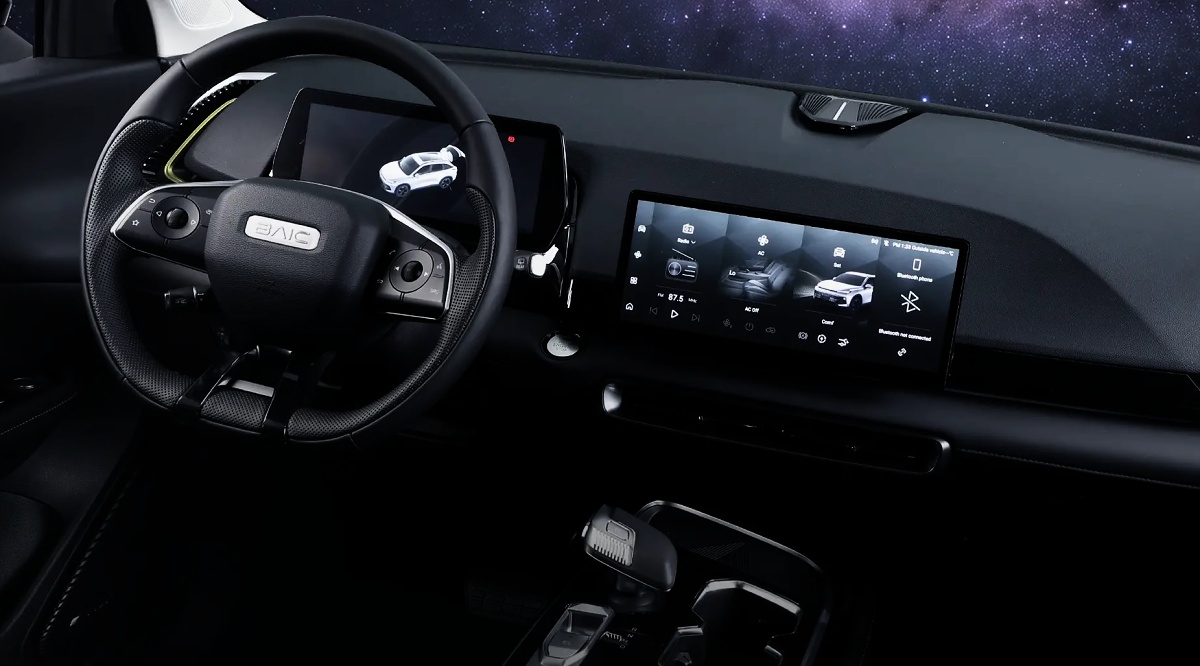 Interior de SUV com volante preto, painel e telas digitais, além de console central.