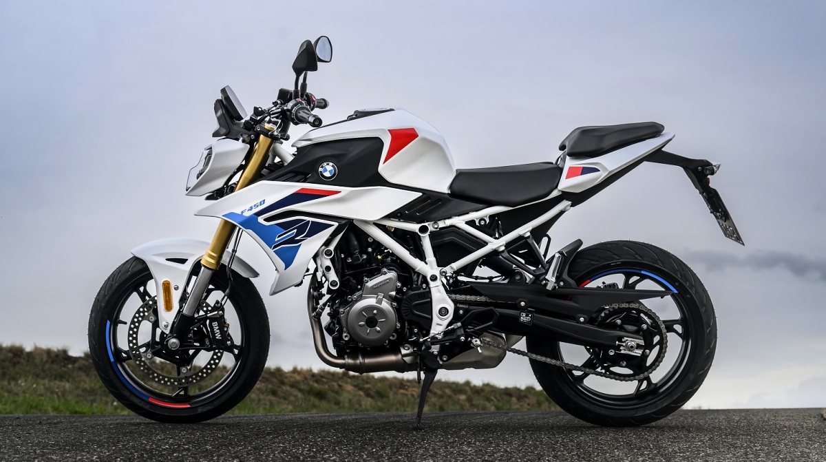 BMW F 450 R branca com detalhes azuis e vermelhos em vista lateral, parada sobre uma estrada.