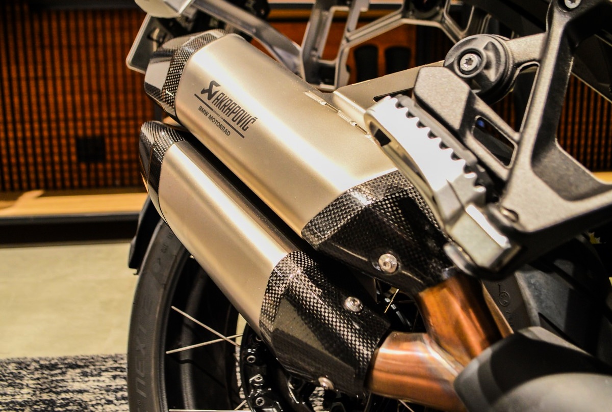 Detalhe do escapamento prateado com inscrição Akrapovic e acabamento escuro em uma BMW Motorrad.
