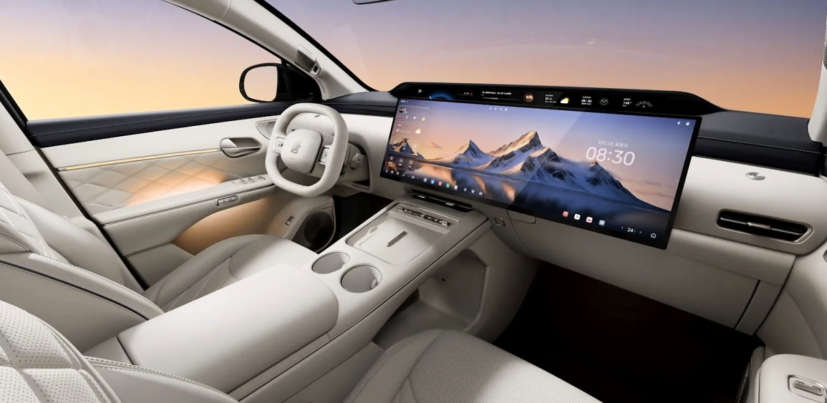 Interior claro do BYD Tang, com volante, console central e uma tela ampla que ocupa boa parte do painel.