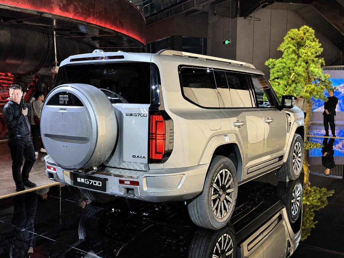 SUV Jetour G700 branco visto de traseira e pela lateral em um salão, com visitantes ao redor.