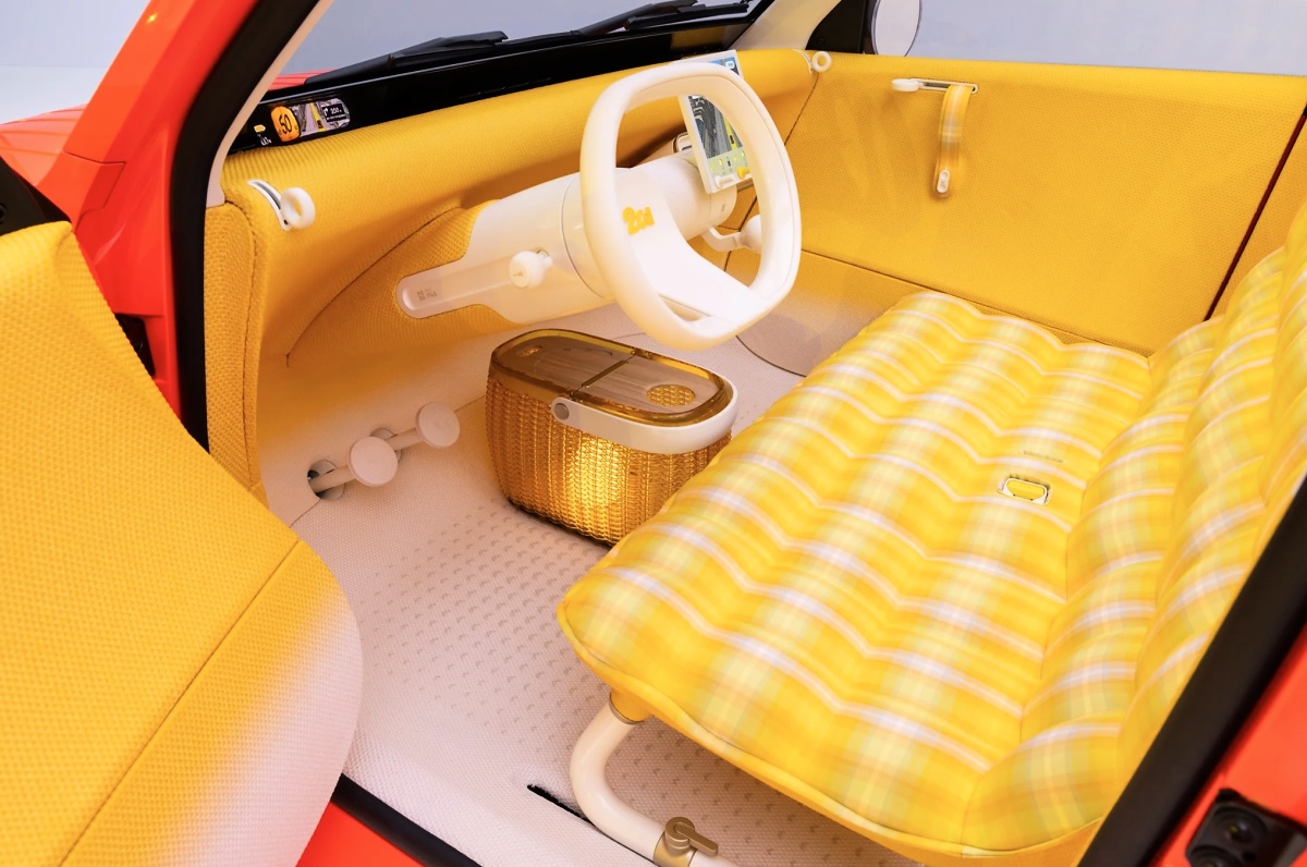 Interior do Citroën 2 CV Concept visto pela lateral, com bancos xadrez, volante branco e painel amarelo.