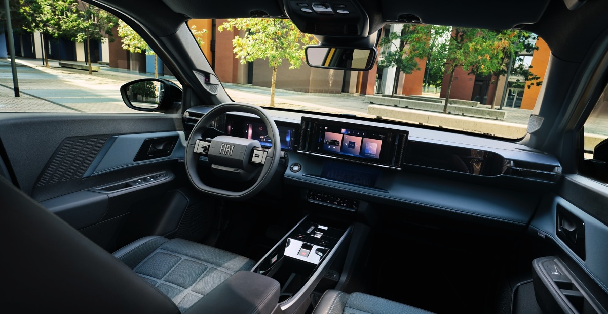 Interior do Fiat Grizzly com volante, painel digital, telas centrais e bancos em tons escuros.