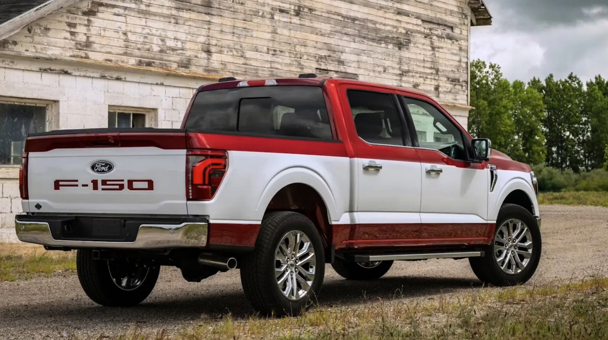 Ford F-150 branca com detalhes vermelhos, vista pela traseira e de lado, diante de um prédio.