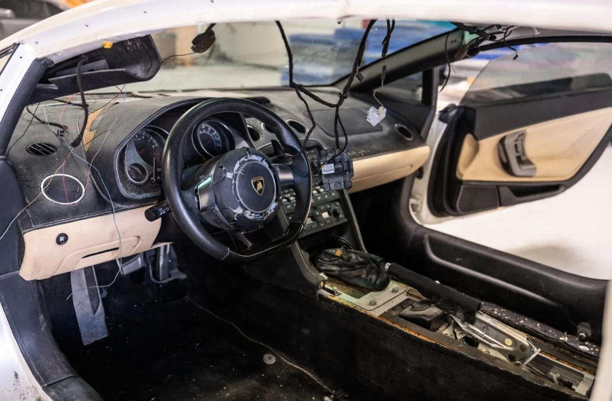 Interior de um Lamborghini Gallardo com volante, painel, fiação exposta e console central desmontado.