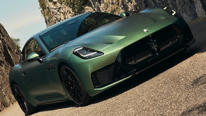 Maserati GranTurismo verde em uma estrada, visto de frente e de lado, com rodas pretas e detalhes escuros na dianteira.