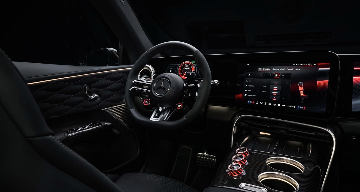 Interior escuro de um Mercedes-AMG GT SUV, com volante de três raios, emblema da Mercedes-Benz e telas no painel.