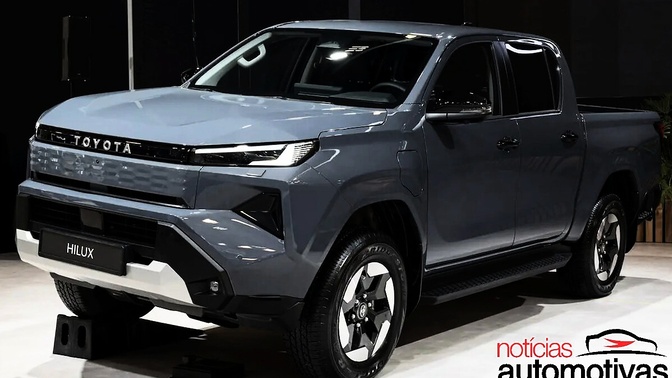 Toyota Hilux cinza vista de frente e de lado em um ambiente interno de exposição.