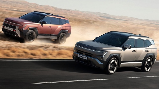 Dois SUVs Hyundai em movimento, um cinza e outro cobre, em uma estrada cercada por terreno árido.