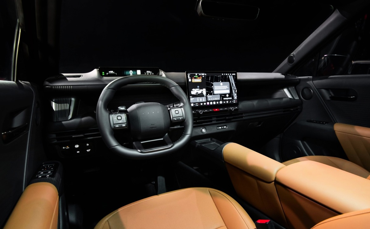 Interior de um Hyundai Tucson com volante, tela central, comandos abaixo do painel e bancos e console em tom caramelo.