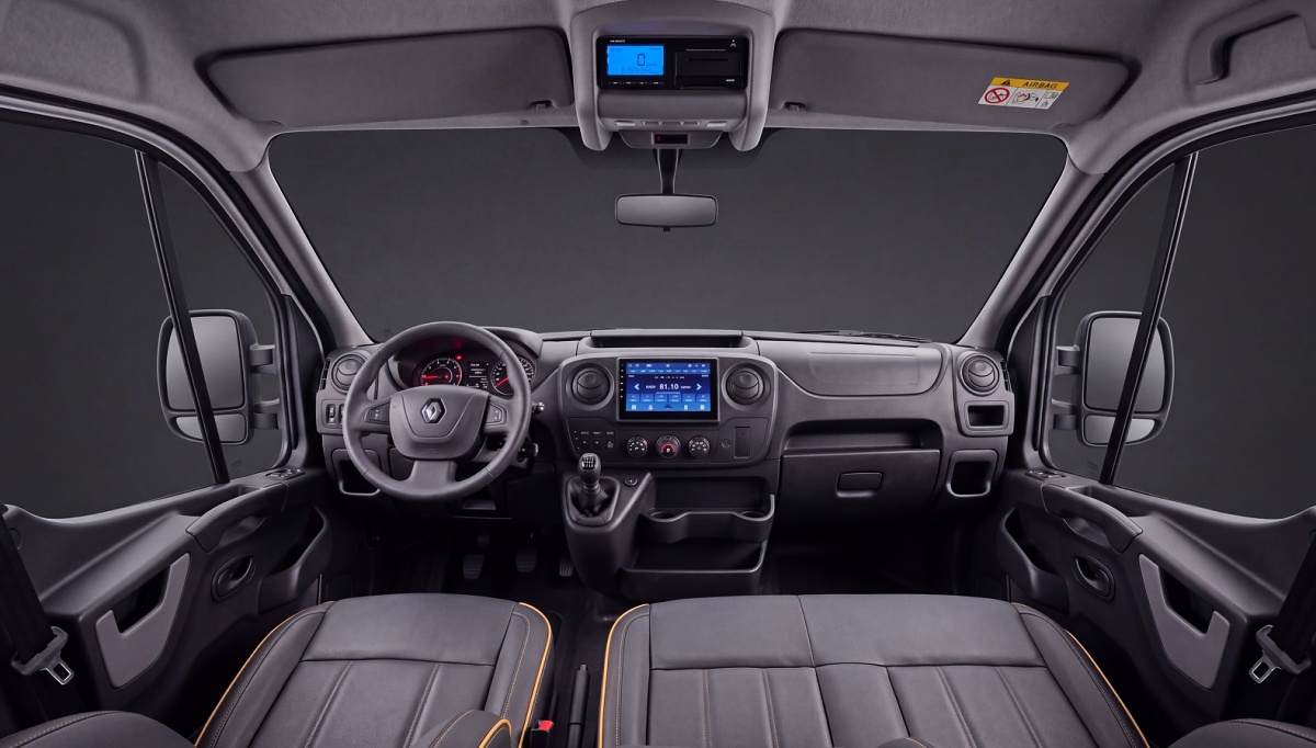 Painel e bancos dianteiros de uma Renault Master, vistos do compartimento de passageiros.