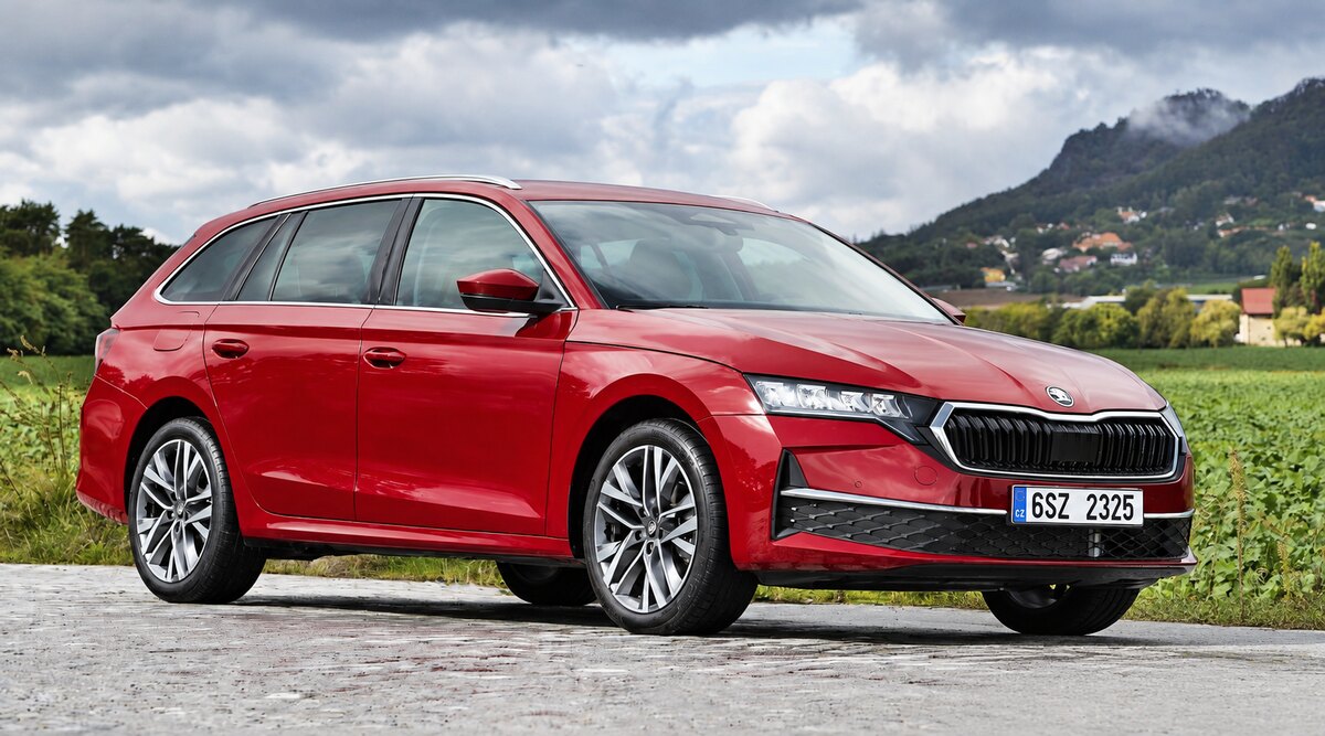 Skoda Octavia vermelho visto de frente e de lado, estacionado em uma estrada junto a um campo.