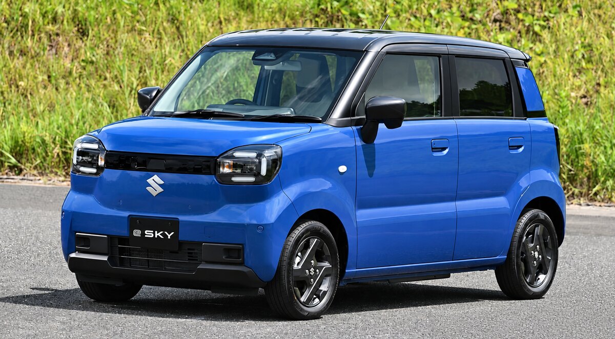 Suzuki e-Sky azul em uma rua, com vegetação ao fundo e o nome do modelo visível na placa dianteira.