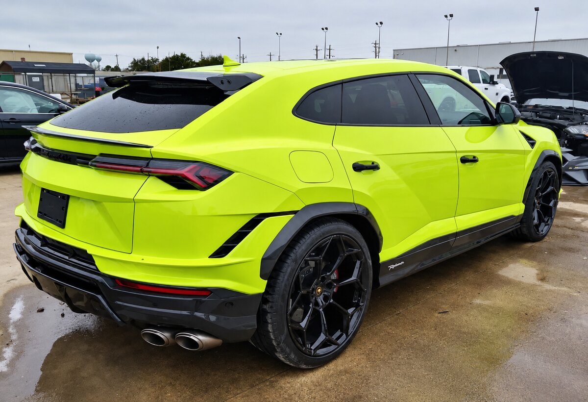 Lamborghini Urus Performante amarelo, com rodas pretas, visto pela traseira em um pátio.