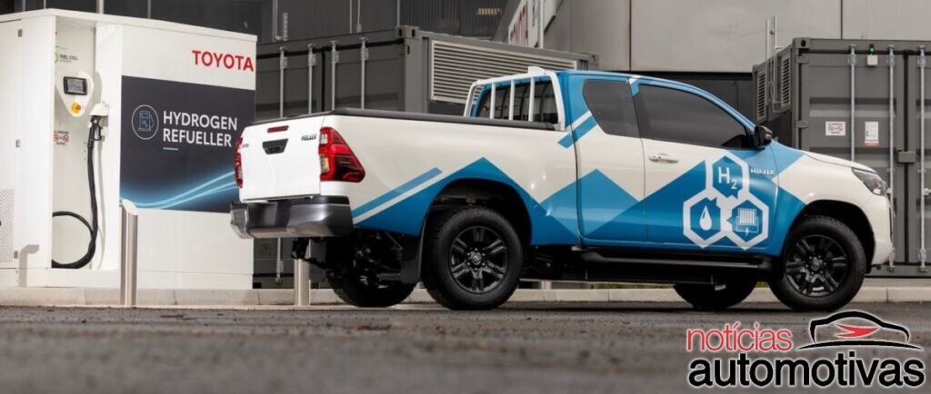 Toyota Hilux branca e azul ao lado de um equipamento com a inscrição Hydrogen Refueller.