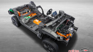 Chassi de automóvel sem carroceria, com motor, rodas, cabos e componentes elétricos em laranja.